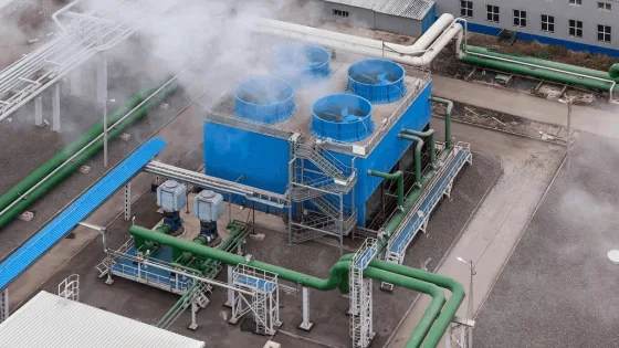 Industrial cooling towers with green pipework at a factory site